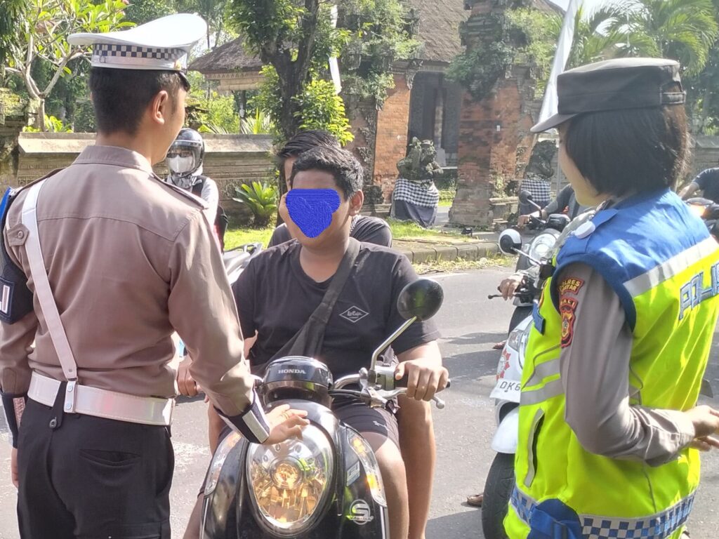 Salah satu anak di Gianyar membawa sepeda motor ke jalan raya.