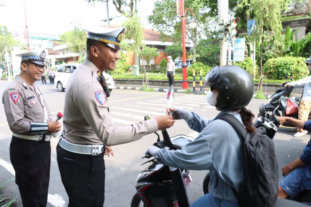 Bunga mawar diberi ke pengendara saat berhenti di lampu merah simpang Ngurah Rai Gianyar.