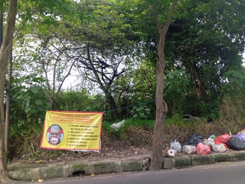 Spanduk bergambar celuluk ini berisi ancaman bagi pembuang sampah sembarangan.