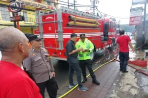 Petugas memadamkan kobaran api di Apotek BWF.