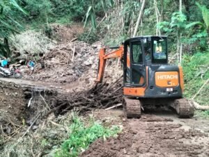 Alat berat diterjunkan oleh BPBD Karangasem untuk menyingkirkan longsor yang menutup akses warga banjar.
