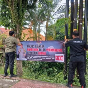 Personel Humas Polres Gianyar memasang spanduk TOLAK PREMANISME di sejumlah sudut jalan.