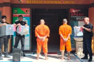 Dua tersangka kasus premanisme, KP dan MM, digiring ke hadapan media dengan tangan diborgol dan mengenakan baju tahanan.