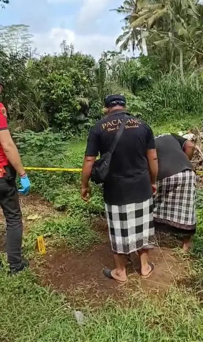 Pecalang dan petugas kepolisian saat olah TKP di kuburan bayi yang diduga bekas digali.