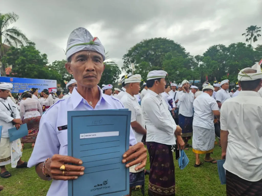 Wayan Tusta (58) memperlihatlam map yang berisi SK PPPK di Lapangan Tanah Aron.