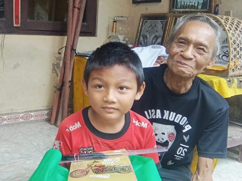 Kakek asuh cucunya Gede Rangga sebagai pengamplas patung.