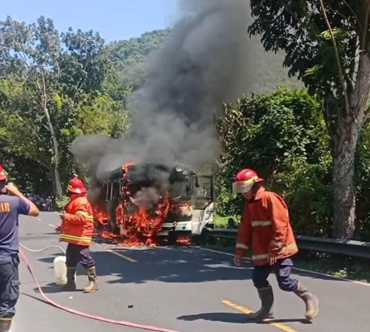 Petugas berusaha membuka selang untuk menyemprotkan air ke titik api.
