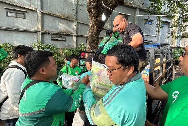 Mitra Pengemudi Grab bergotong royong menurunkan ratusan sembako untuk warga terdampak banjir yang mengungsi di Posko Cokroaminoto, Dauh Puri Kaja, Denpasar, Bali (17/09).