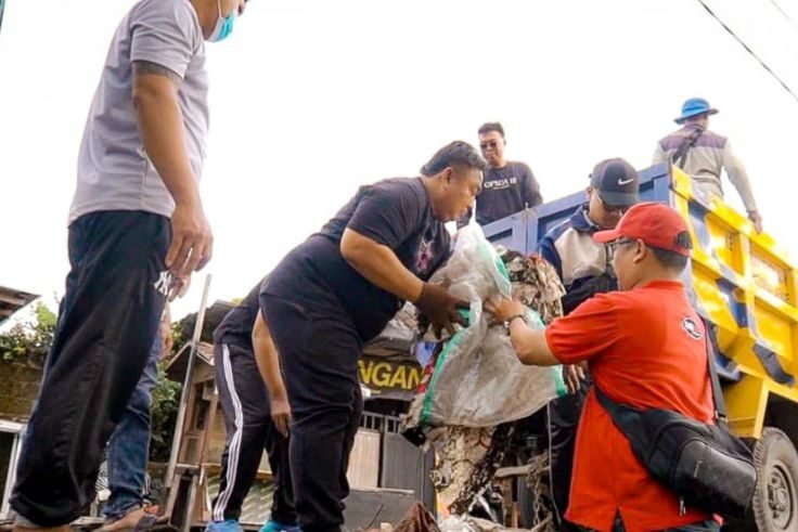 Nyoman Parta bersama relawan mengangkat tumpukan sampah.