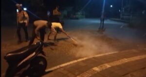 Warga dan polisi membersihkan tumpahan koral di perempatan Tojan, Klungkung.