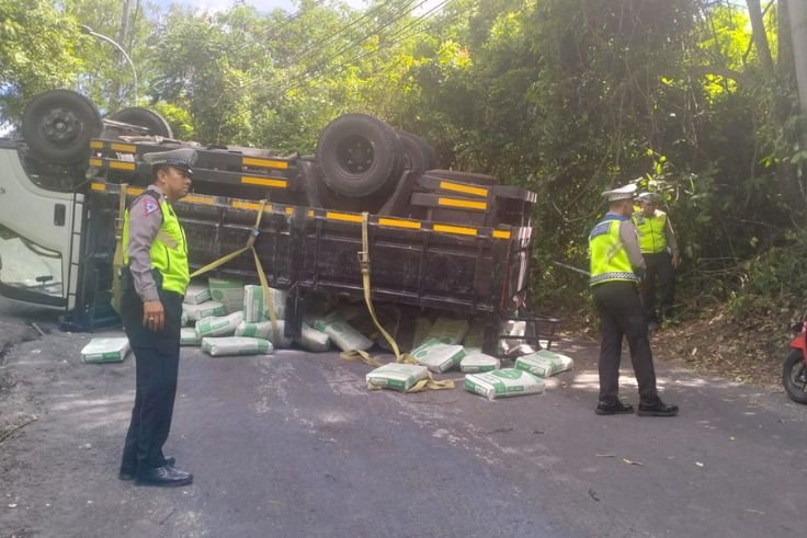 Truk bermuatan semen terguling di Tanjakan Pura Goa Gong, Jimbaran, akibat gagal menanjak.