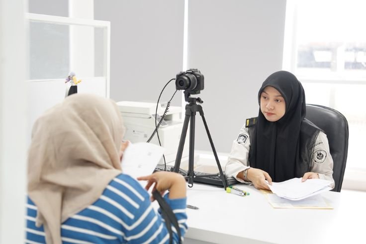 Ilustrasi Petugas Imigrasi melayani masyarakat yang mengurus dokumen paspor di kantor imigrasi.
