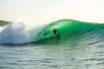 A surfer rides a powerful barrel at Bali's iconic Padang Padang Beach.
